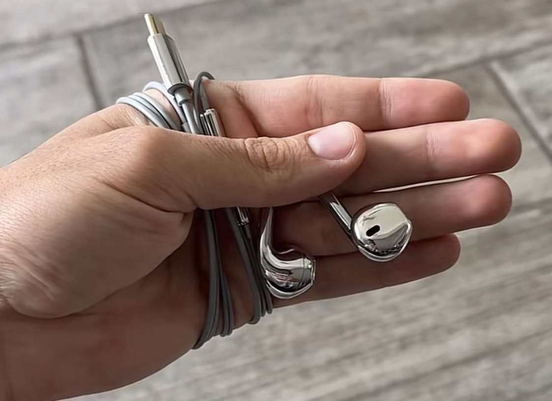 Phantom Platinum silver earphones resting in a customer's palm outdoors